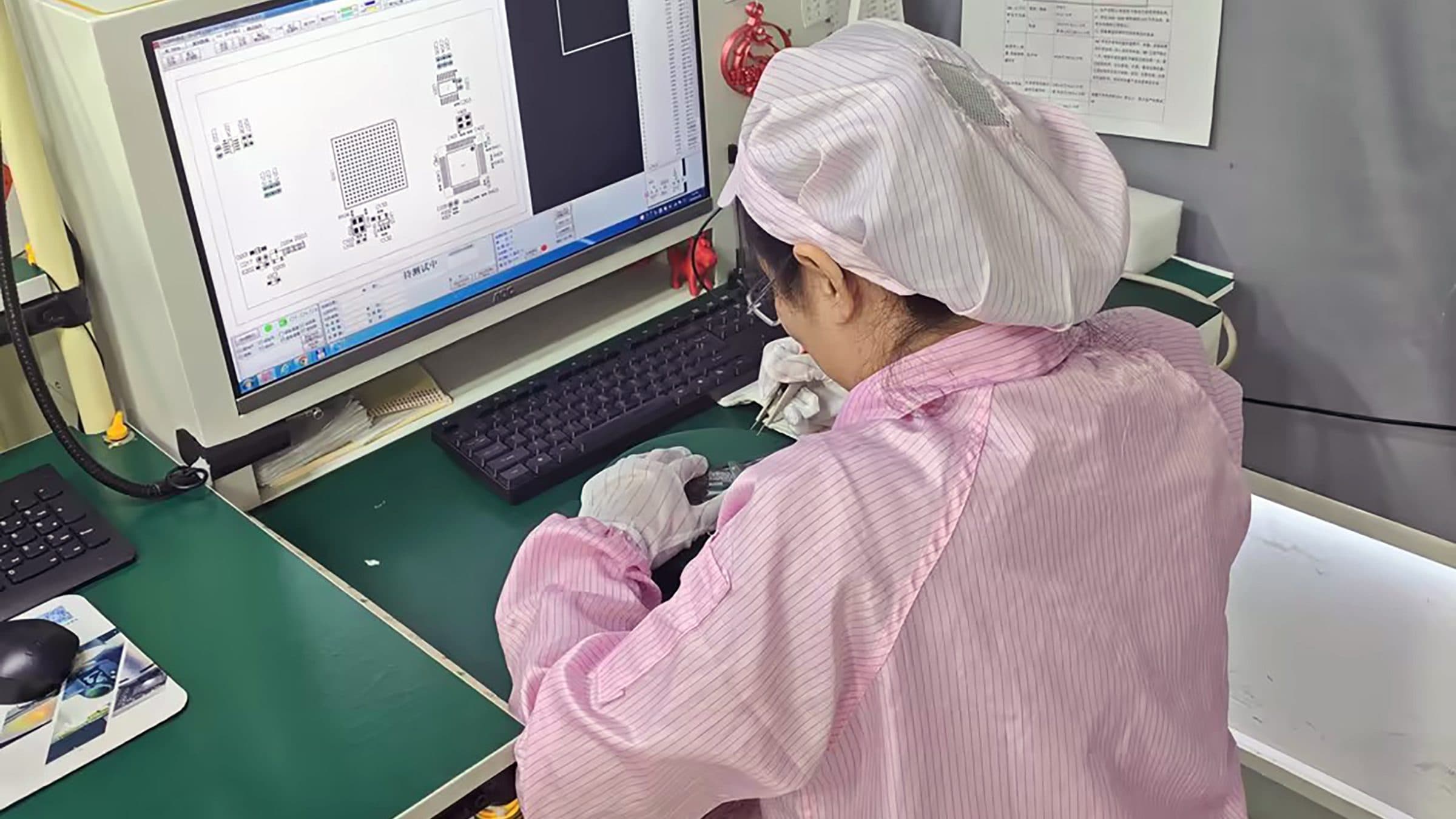品质员工在首件检测工位核对电路板与屏幕图纸